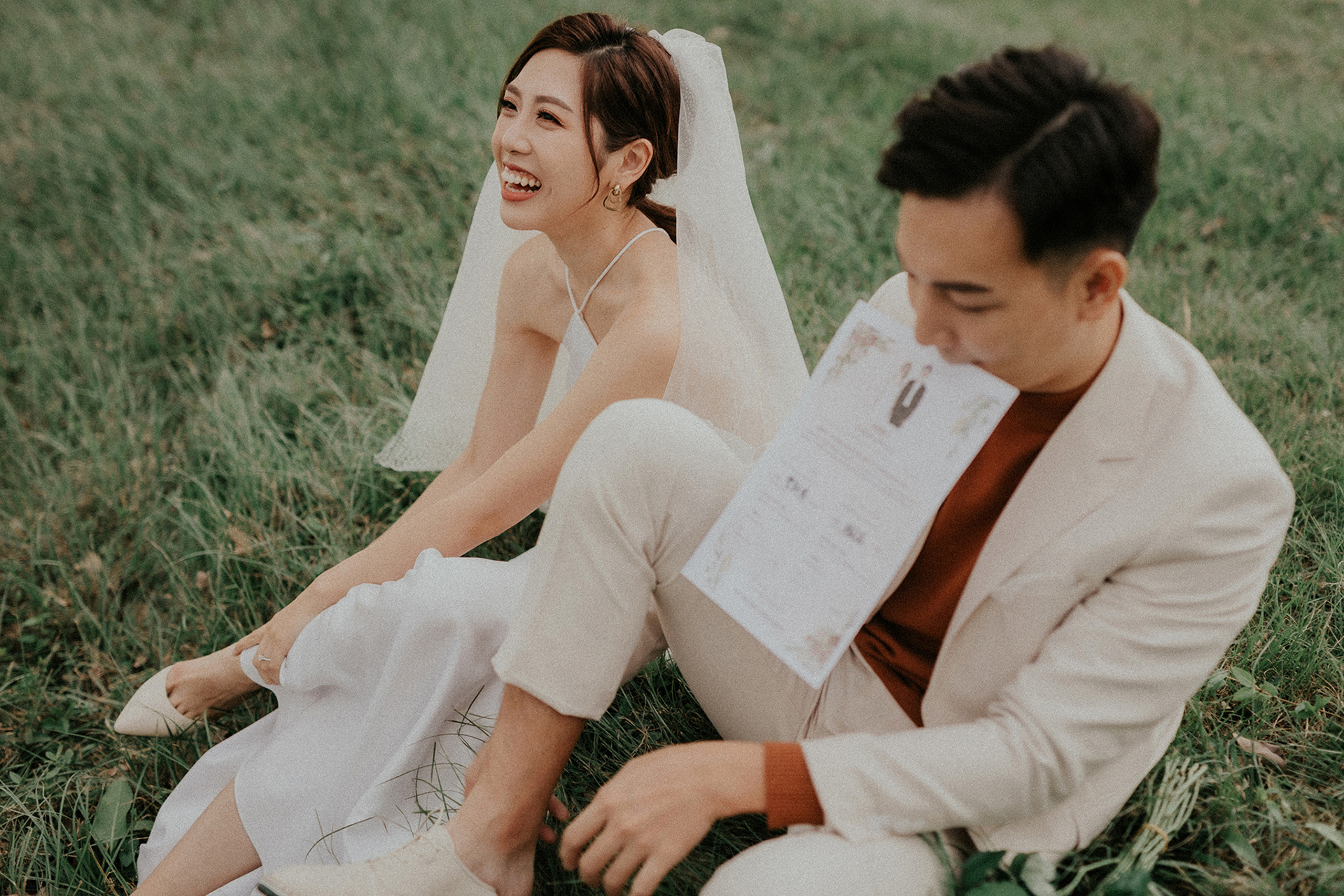 結婚登記拍攝 台北河堤生活婚紗 新娘笑著坐草地 新郎咬結婚書約